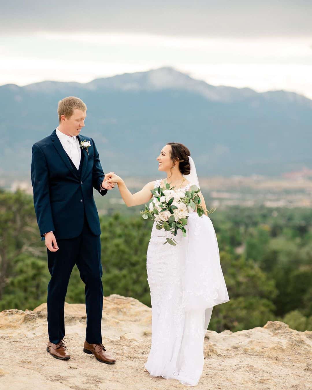 wedding couple during cocktail hour taking portraits with mountains in the background near the venue